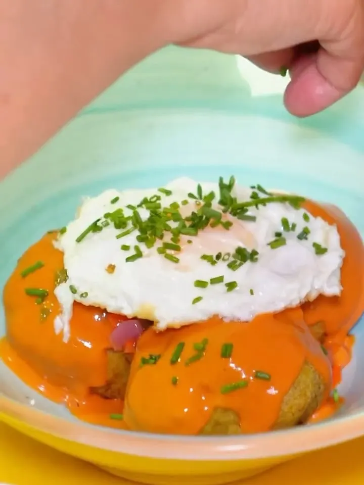 Un huevo poché se coloca sobre patatas con salsa