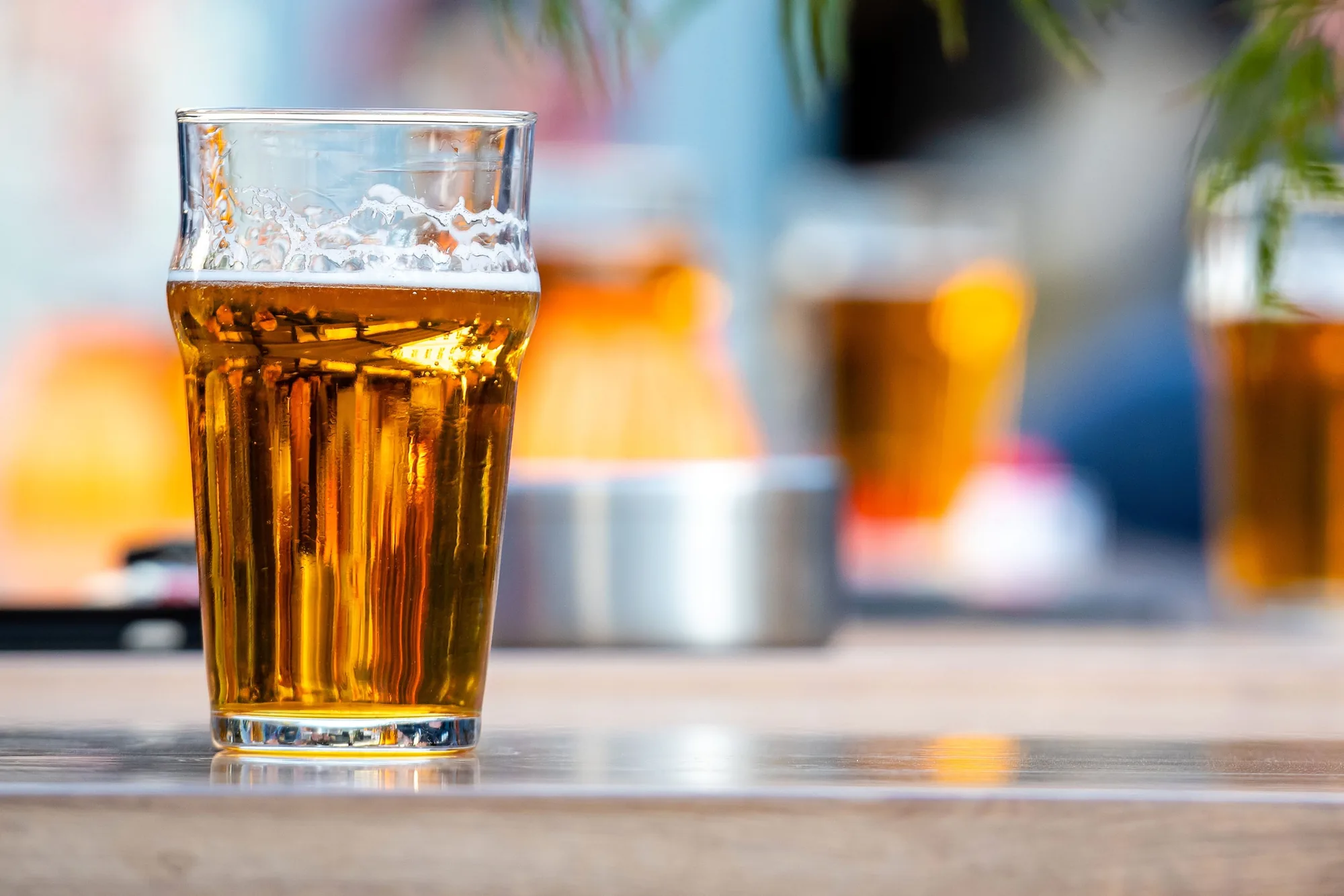 Vaso alto de cerveza dorada sobre la barra, con luz de día